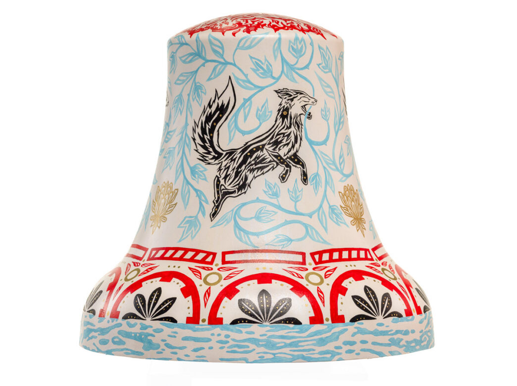Bell sculpture titled “Heartbeat of the Fox” from Philadelphia250’s Bells Across PA, featuring a stylized black fox mid-leap surrounded by light blue vines and foliage. The cream-colored surface is accented with red and gold decorative patterns near the top and middle, and a band of flowing blue water motifs wraps around the base.
