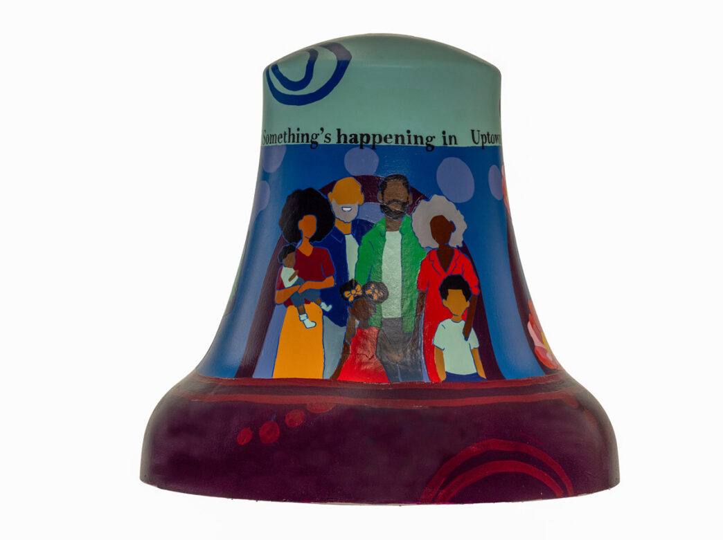 Bell sculpture titled “Keeping It In The Family” from Philadelphia250’s Bells Across PA, featuring a stylized multigenerational family standing together. Figures include adults and children in bright, simplified colors, set against a blue background with circular patterns. The phrase “Something’s happening in Uptown” appears near the top, emphasizing community, family, and neighborhood pride in Ogontz.