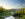A sweeping view from Chimes Tower overlooks Longwood Gardens, with manicured lawns, winding paths, fountains, and conservatory buildings bathed in warm evening light.