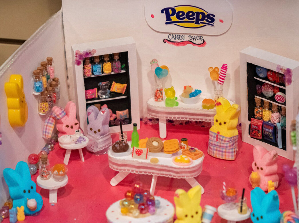 A miniature Peeps-themed candy shop display features colorful marshmallow bunny figures, tiny candy jars and sweets arranged around small tables.