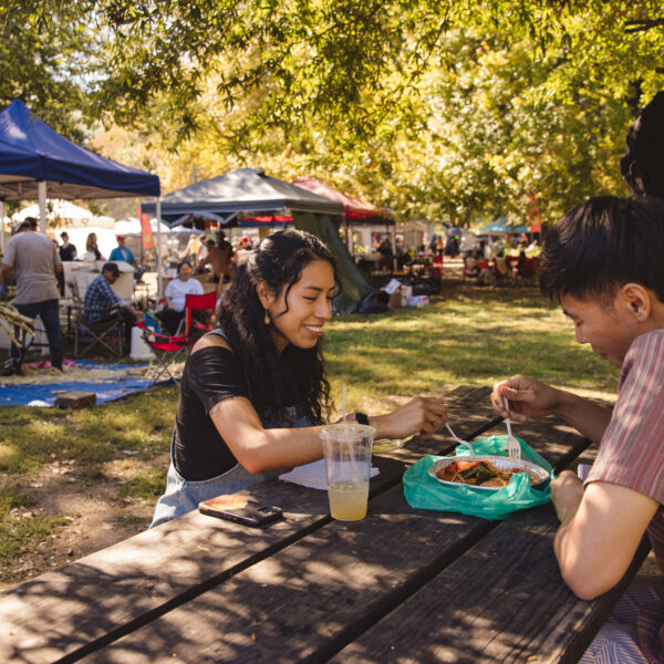 Un couple partage de la nourriture sur une table en bois au Southeast Asian Market de Philadelphie.