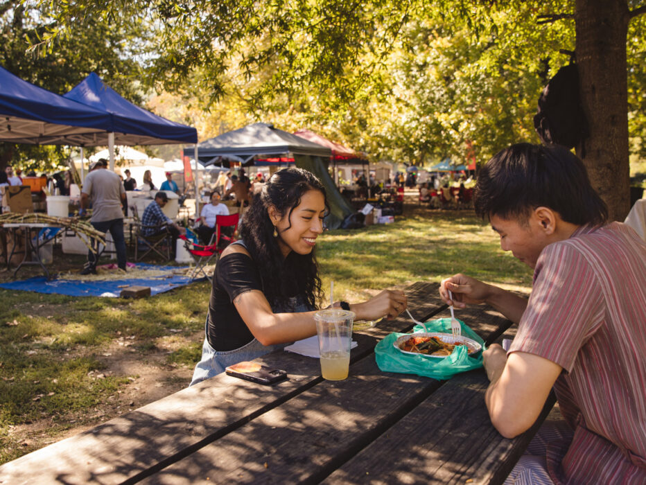 A couple shares food on a wooden table at the Southeast Asian Market in Philadelphia.