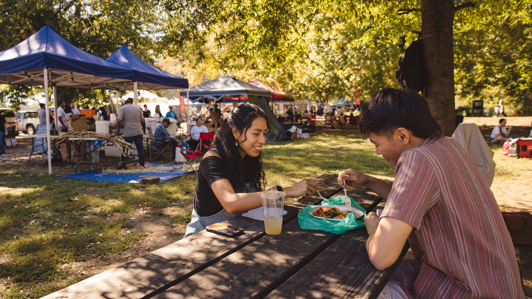 Una pareja comparte la comida en una mesa de madera en el mercado del sudeste asiático de Filadelfia.