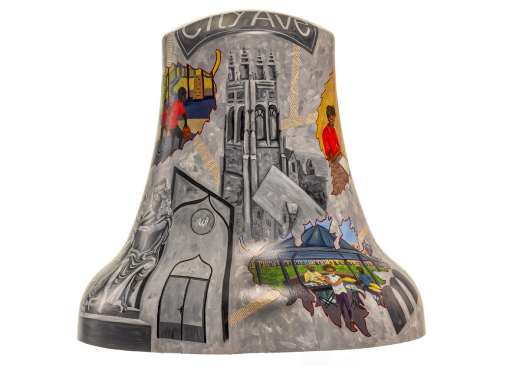 Bell sculpture titled “Stories Tolled” from Philadelphia250’s Bells Across PA, featuring a grayscale architectural backdrop of buildings and a church tower labeled “City Ave.” Colorful inset scenes appear throughout, showing moments of everyday life such as children playing basketball, people gathering, and community activities, highlighting the layered stories and experiences of the Wynnefield neighborhood.