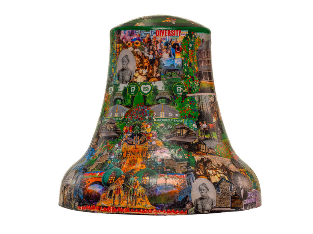 Bell sculpture titled “Tapestry of Hidden History” from Philadelphia250’s Bells Across PA, featuring a dense collage of historical photographs, community scenes, and landmarks. The design layers images of diverse people, historic homes, bridges, and local parks with greenery and flowers, alongside words like “DIVERSITY,” creating a rich visual narrative of Mt. Airy’s cultural history and community life.