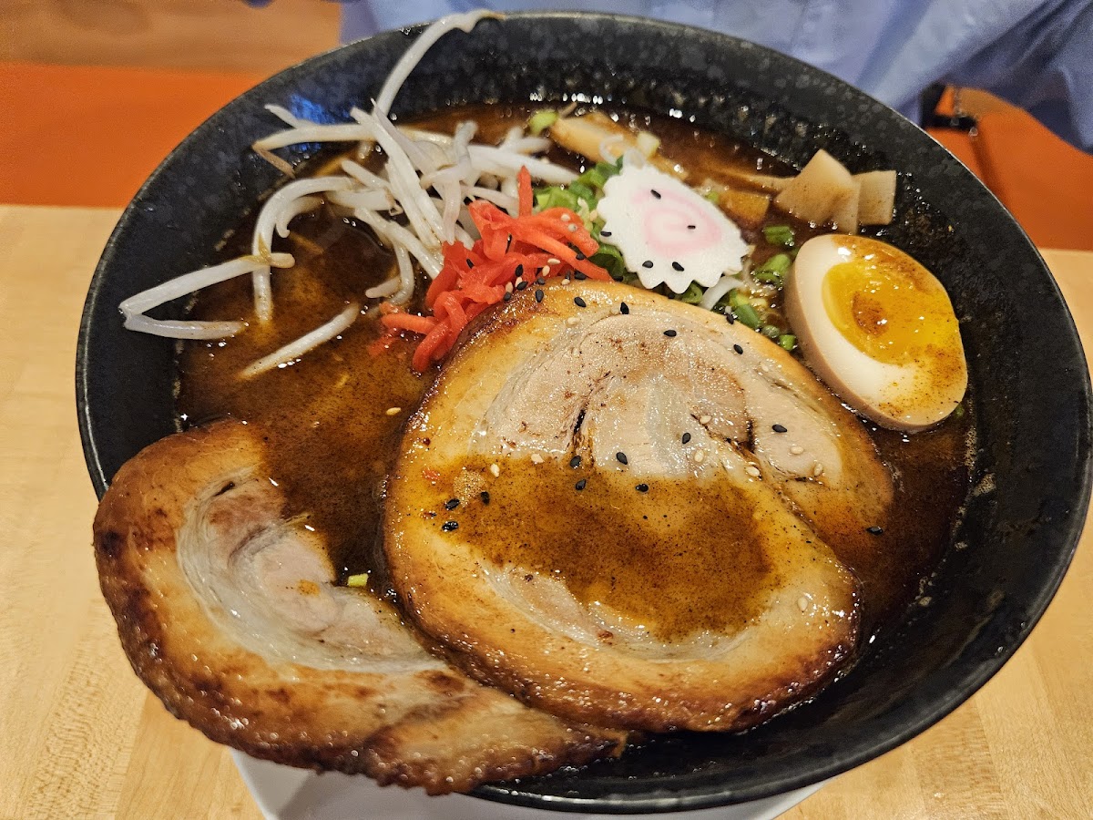 A bowl of ramen from Tataki Ramen and Sushi in West Philadelphia topped with sliced pork, a soft-boiled egg, bean sprouts, pickled ginger and scallions in a rich broth.