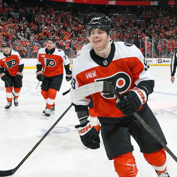 Several Philadelphia Flyers players skate off the ice while smiling.