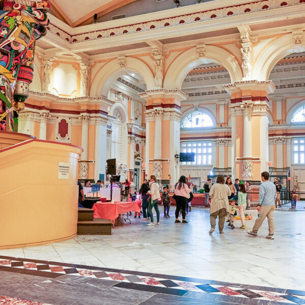 A crowd of visitors walk on a marble floor inside the Please Touch Museum.