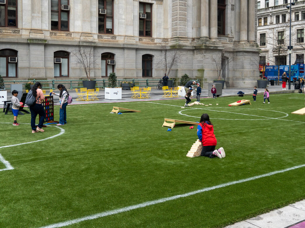 Crianças brincam em um campo de futebol de grama montado do lado de fora do City Hall da Filadélfia.