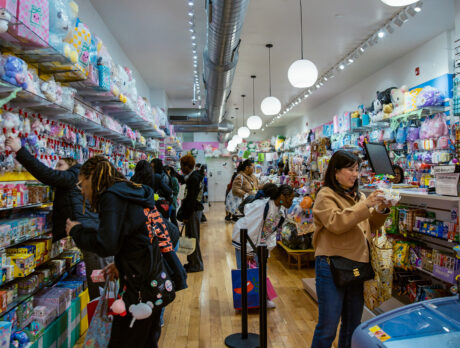 A group of shoppers peruse colorful merchandise, including stuffed animals and playing cards, at Asia Crafts