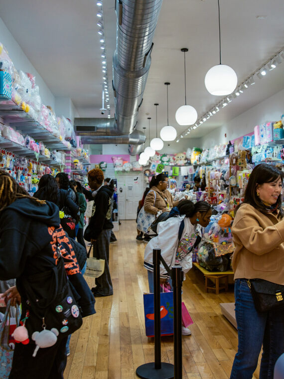 A group of shoppers peruse colorful merchandise, including stuffed animals and playing cards, at Asia Crafts
