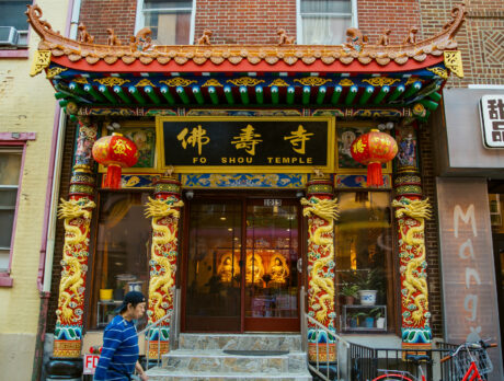 The ornately decorated entrance to Fo Shou Temple in Philadelphia's Chinatown features traditional Chinese architectural elements including curved eaves, golden dragons, red lanterns, and elaborately carved pillars with traditional designs.