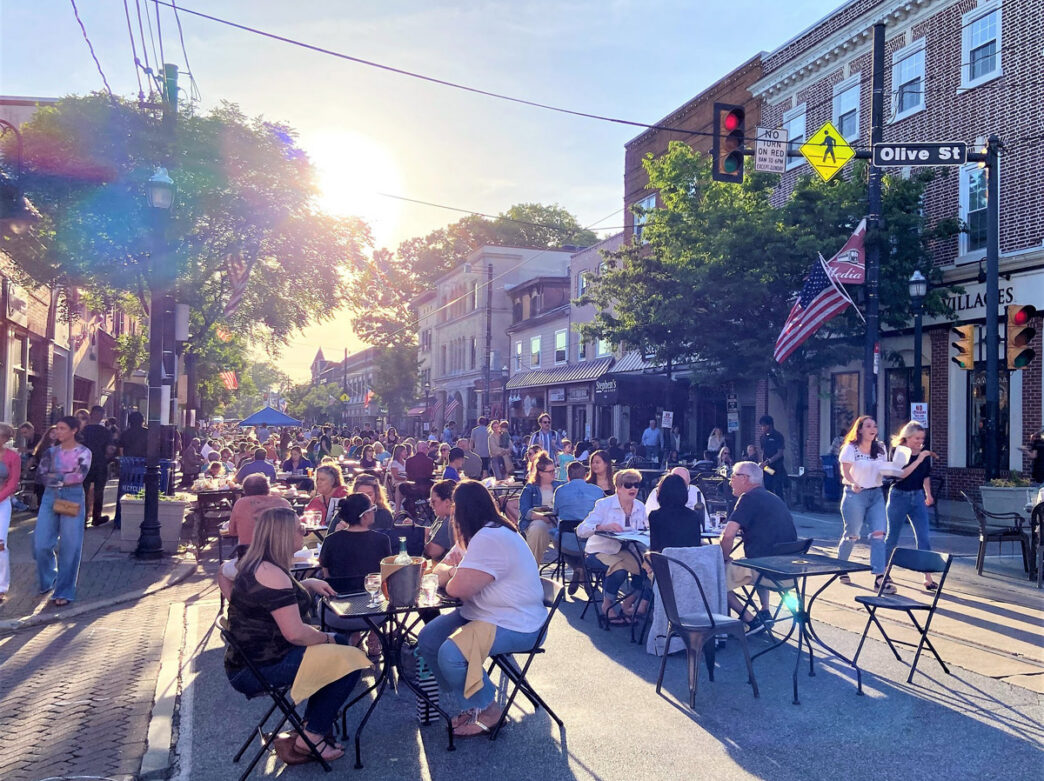 Outdoor diners enjoying Dining Under the Stars on a street in Media, PA at sunset with historic brick buildings and bustling crowds.