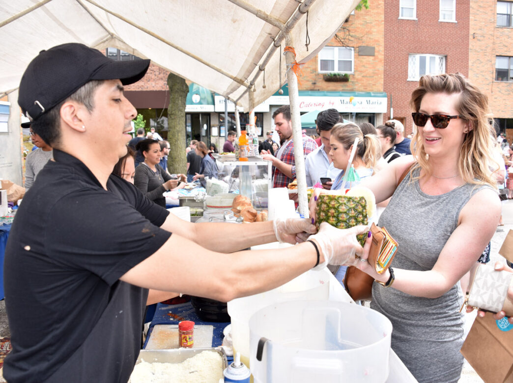 A woman receives a drink in a pineapple from a vendor at Flavors on the Avenue on East Passyunk Avenue.