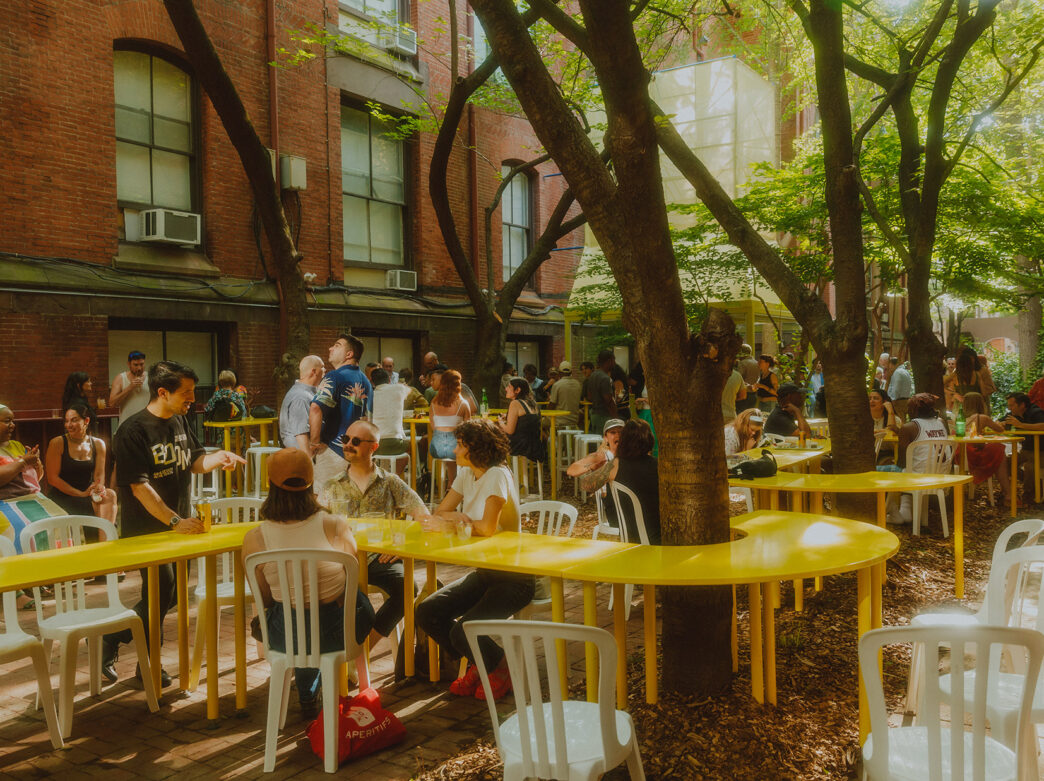 Mensen zitten rond boomstammen terwijl een gele tafel zich rond een boom wikkelt bij Frankie's Summer Club in Philadelphia