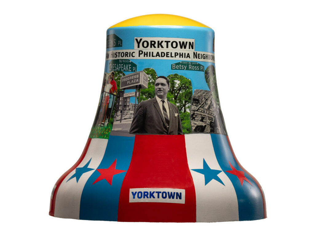 Patriotic-themed bell titled “Pride of Yorktown” featuring red, white, and blue stripes, stars, and collage images of neighborhood landmarks and figures, representing Philadelphia’s Yorktown neighborhood as part of Philadelphia250’s Bells Across PA.