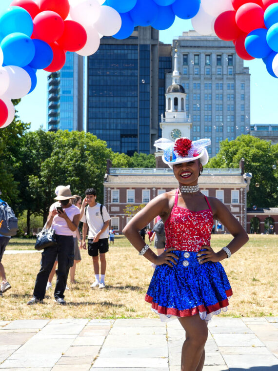 Tres personas con atuendos patrióticos frente al Independence Hall durante el evento «Red White & Blue To Do».