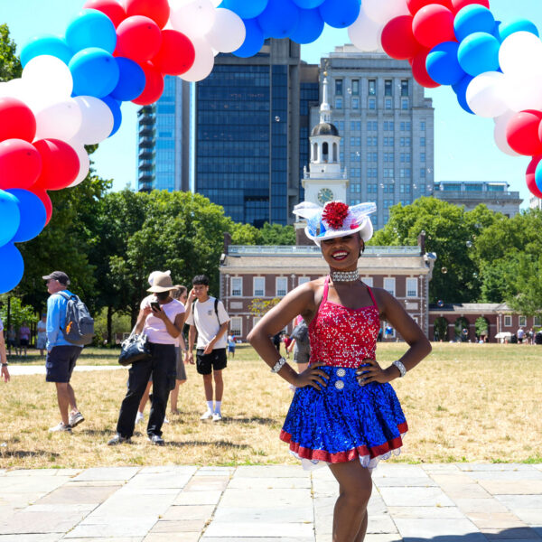 Três pessoas em trajes patrióticos em frente ao Independence Hall durante o Red White & Blue To Do.