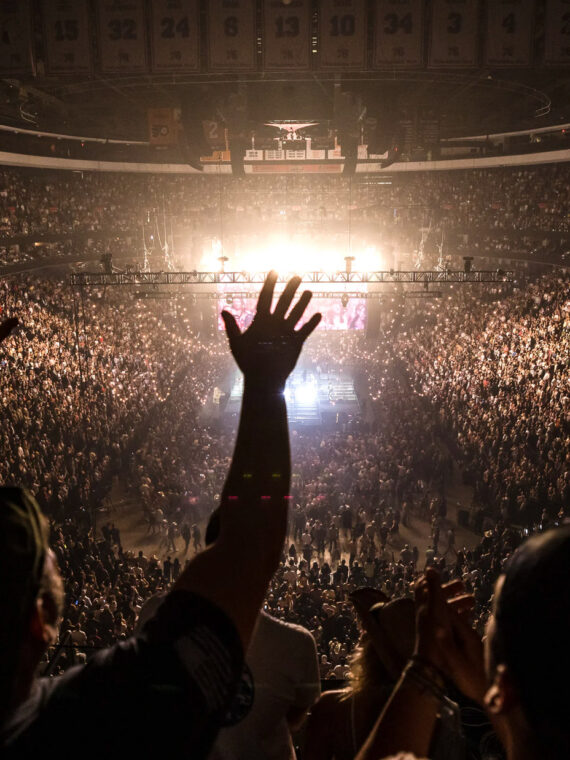Crowd fills Xfinity Mobile Arena in Philadelphia during a concert, with thousands of fans cheering and raising their hands toward a brightly lit stage at center.