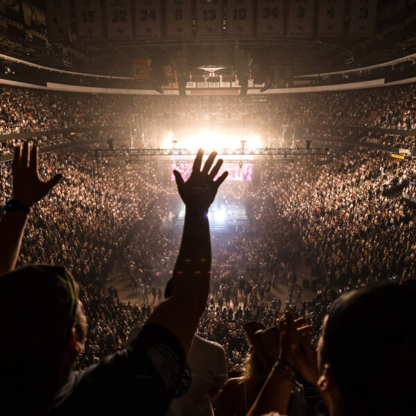 Crowd fills Xfinity Mobile Arena in Philadelphia during a concert, with thousands of fans cheering and raising their hands toward a brightly lit stage at center.