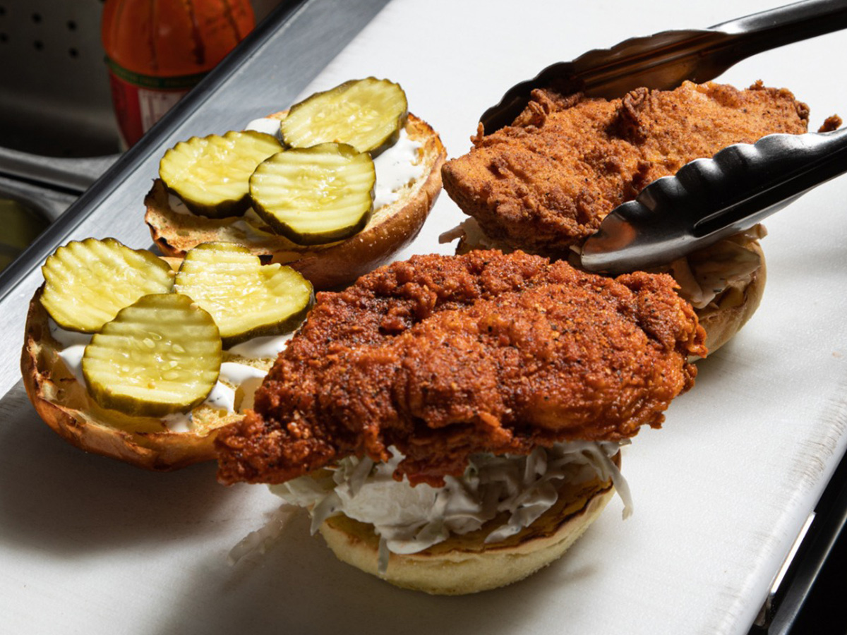 Two fried chicken sandwiches sit open-faced on a white countertop.