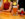 A man and a woman sit at a bar. The man holds a pint full of beer while the woman takes a sip of hers.