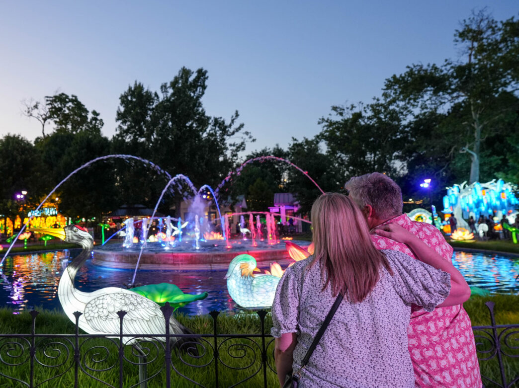 A couple embraces while viewing colorful illuminated displays and glowing fountains at the Chinese Lantern Festival in Philadelphia’s Franklin Square at dusk.