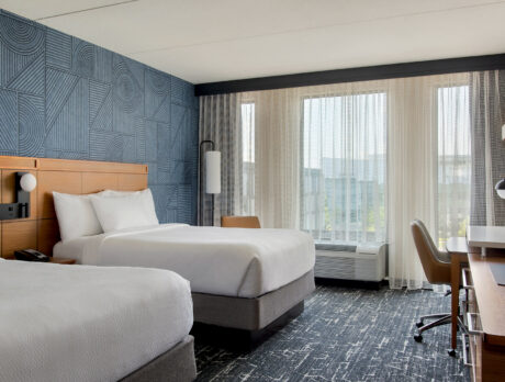 Une chambre d'hôtel très lumineuse, dotée de moquettes et de murs bleus, avec deux grands lits, au Courtyard Philadelphia South at The Navy Yard