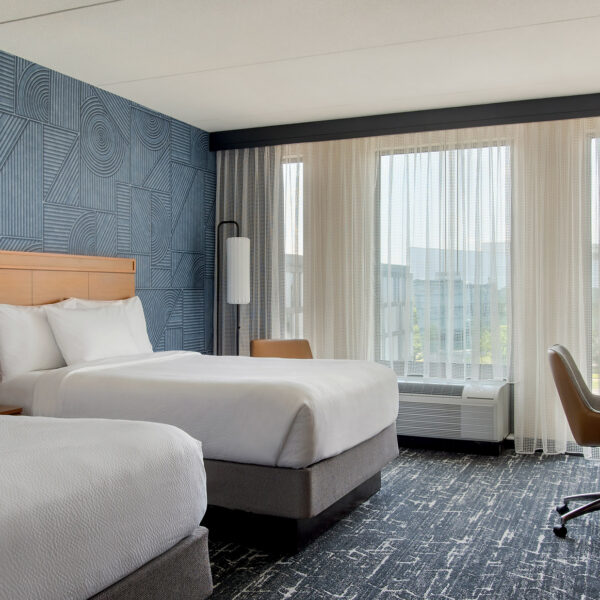 Une chambre d'hôtel très lumineuse, dotée de moquettes et de murs bleus, avec deux grands lits, au Courtyard Philadelphia South at The Navy Yard