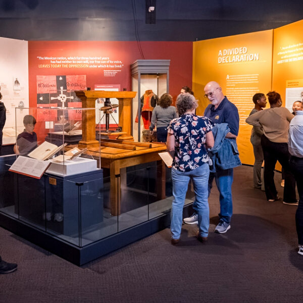 Visitors explore 'The Declaration's Journey' exhibition at the Museum of the American Revolution, examining displays about Independence Movements and A Divided Declaration with interactive exhibits and historical artifacts.
