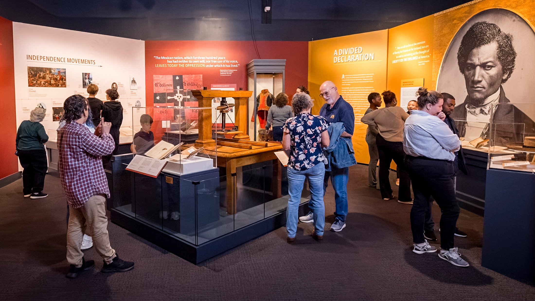 Los visitantes recorren la exposición 'El viaje de la Declaración' en el Museum of the American Revolution, donde pueden examinar las vitrinas dedicadas a los movimientos independentistas y a «Una declaración dividida» a través de exposiciones interactivas y objetos históricos.