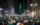 A large crowd of Eagles fans gather in front of City Hall in Philadelphia to celebrate a championship win. The City Hall building is lit up in green.