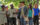 Un guide en costume colonial du XVIIIe siècle conduit un groupe de visiteurs lors d'une promenade historique dans Philadelphie, à l'ombre de grands arbres verts.