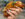 A woman with painted nails holds a crispy taco at La Catrachita Taqueria