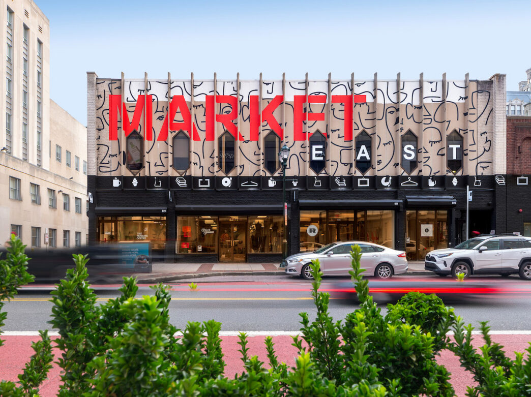 Modern storefront of Meantime on Market in Philadelphia features bold red lettering and artistic face designs on its distinctive facade, located on a busy urban street.