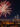 Fireworks burst over the Benjamin Franklin Parkway and Center City Philadelphia skyline during a Fourth of July celebration at night. The illuminated Philadelphia Museum of Art and city skyscrapers are visible beneath colorful fireworks lighting up the sky.