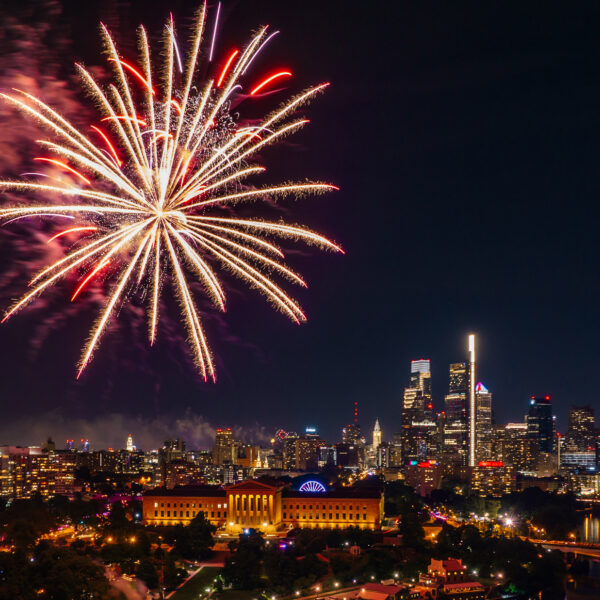Vuurwerk barst los boven de Benjamin Franklin Parkway en de skyline van Center City Philadelphia tijdens een nachtelijke viering van Fourth of July. De verlichte Philadelphia Museum of Art en wolkenkrabbers van de stad zijn zichtbaar onder kleurrijk vuurwerk dat de hemel verlicht.