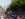Una multitud se congrega a lo largo de la avenida Benjamin Franklin Parkway en Filadelfia durante la celebración del «Fourth of July Party on the Parkway». La gente se sienta y pasea bajo las calles arboladas, con el Philadelphia City Hall visible al fondo en un soleado día de verano.