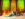 Un artista posa en las escaleras del Philadelphia Museum of Art durante la gala ’Promenade & L.U.V. Awards» de PhillyPride365, sosteniendo una gran bandera arcoíris junto a otros artistas. El evento nocturno cuenta con coloridas proyecciones de luz y la estatua dorada de Diana del museo como telón de fondo.