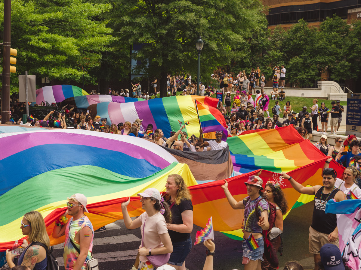 Los participantes llevan una gran bandera arcoíris por las calles durante la Marcha del Orgullo de Filadelfia, con una multitud congregada a lo largo del recorrido.