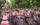 Una colorida banda de percusión actúa durante la Marcha del Orgullo de Filadelfia, mientras los músicos, ataviados con trajes adornados con motivos arcoíris, desfilan por una calle arbolada. La multitud se congrega a lo largo del recorrido, ondeando banderas del orgullo y vitoreando durante la celebración al aire libre.