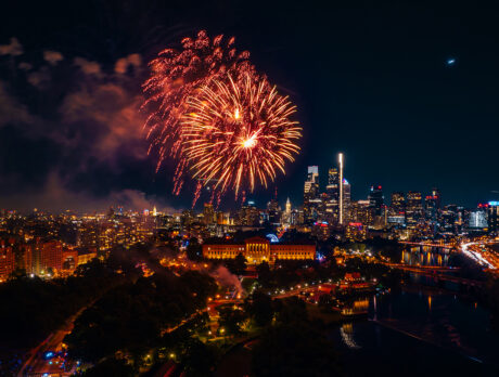 Fireworks burst above the Philadelphia skyline at night, illuminating the Benjamin Franklin Parkway, the Philadelphia Museum of Art and Center City skyscrapers during a Fourth of July celebration.