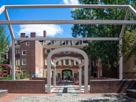 The white steel "ghost structure" marks the footprint of Benjamin Franklin's former home, with historic brick houses visible in the background.