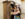 Two participants search through a large wooden wardrobe inside a historic building during CLUE: A Walking Mystery in Philadelphia. Smiling as they examine coats and clues hidden inside the cabinet, they take part in the interactive mystery experience.