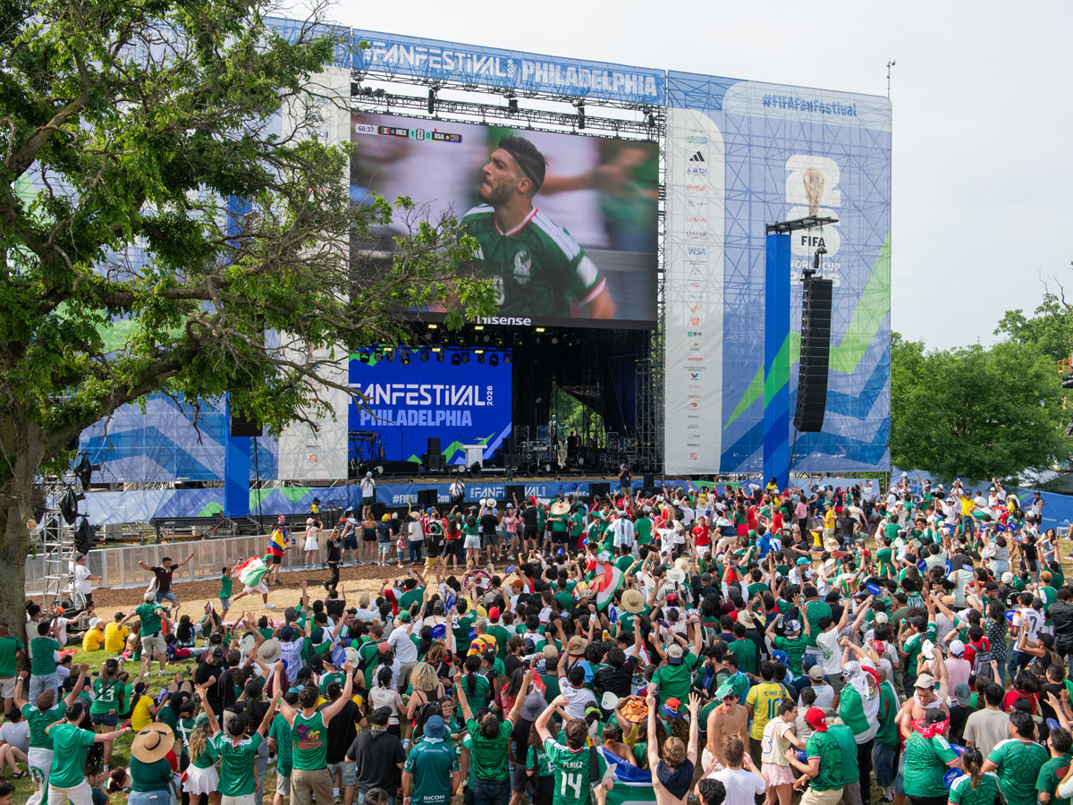 A large crowd of people cheer in front of an outdoor screen during FIFA Fan Festival, broadcasting the Mexico FIFA World Cup game
