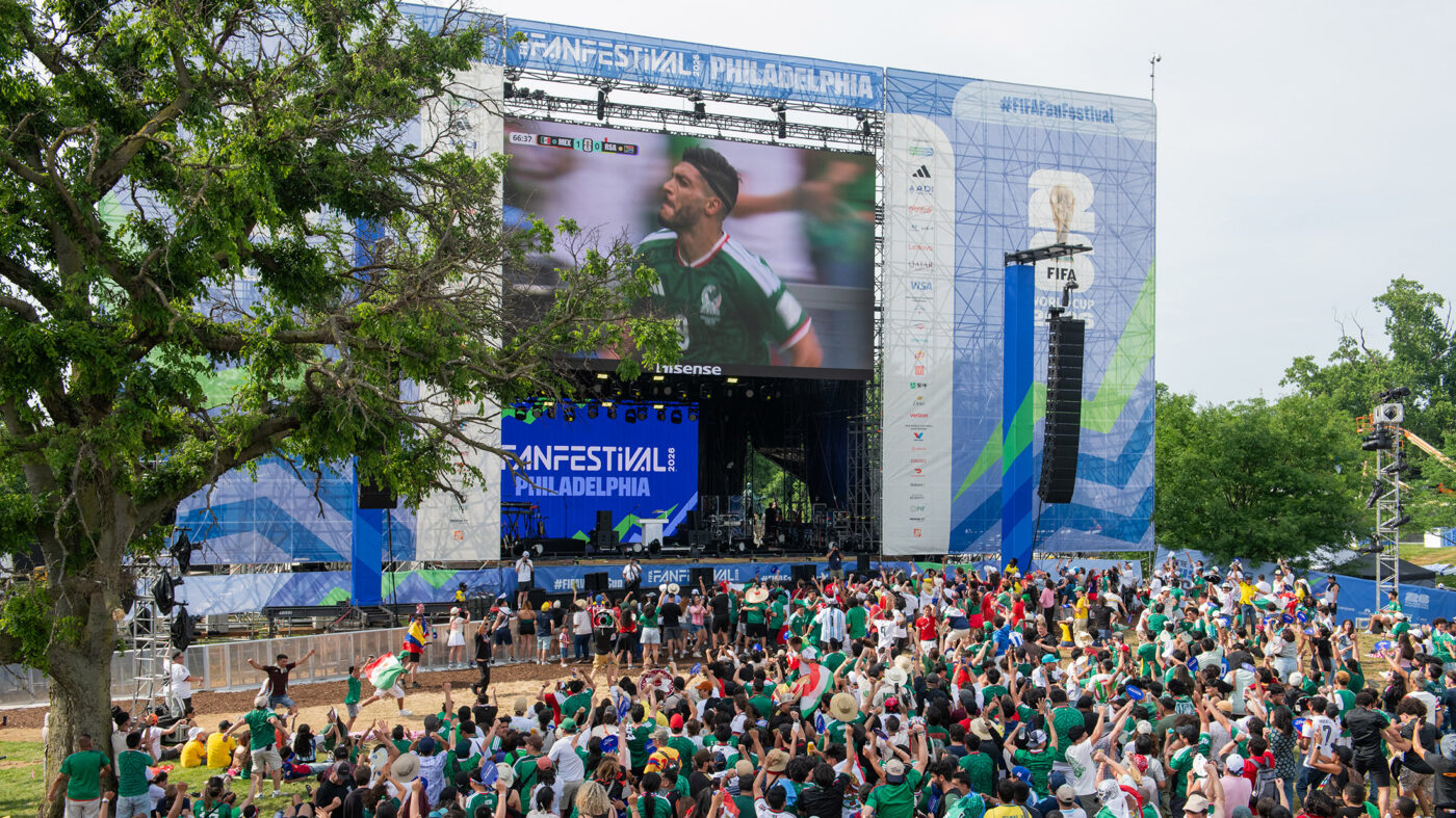 Una gran multitud de personas vitorea frente a una pantalla al aire libre durante el Festival de los Fan de la FIFA, donde se transmite el partido de México en la Copa Mundial de la FIFA.