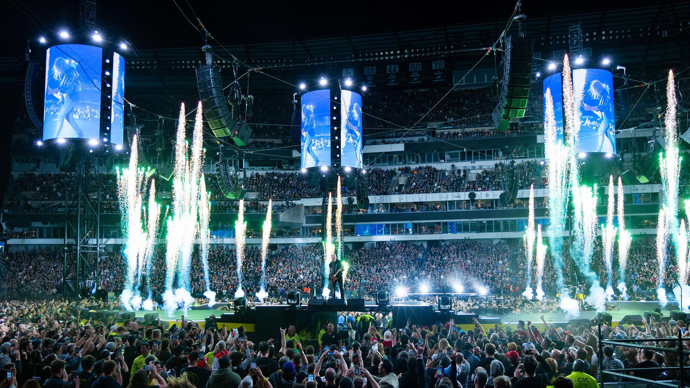 Het Lincoln Financial Field zit bomvol terwijl de metalband optreedt op een rond podium in het stadion, omringd door torenhoge videoschermen, spectaculair groen vuurwerk en concertverlichting.
