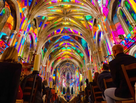 Visitors sit inside Philadelphia’s Cathedral Basilica of Saints Peter and Paul as colorful projected light fills the soaring Gothic arches and vaulted ceiling during the Luminescence light show.
