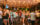 Crowd of patrons socializing and enjoying drinks at Morgan’s Pier in Philadelphia, gathered beneath strings of warm café lights on the waterfront bar’s open-air deck at night.