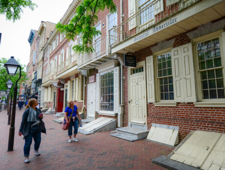 Les visiteurs se promènent le long de Market Street, devant des bâtiments historiques en briques aux volets couleur crème, parmi lesquels l'imprimerie de Benjamin Franklin.